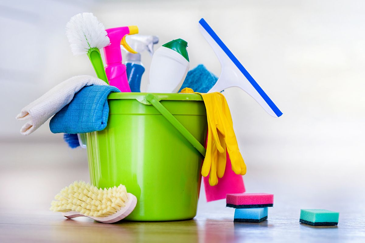 Eimer mit verschiedenen Reinigungsutensilien wie Bürsten, Sprühflaschen, Tüchern und Schwämmen.