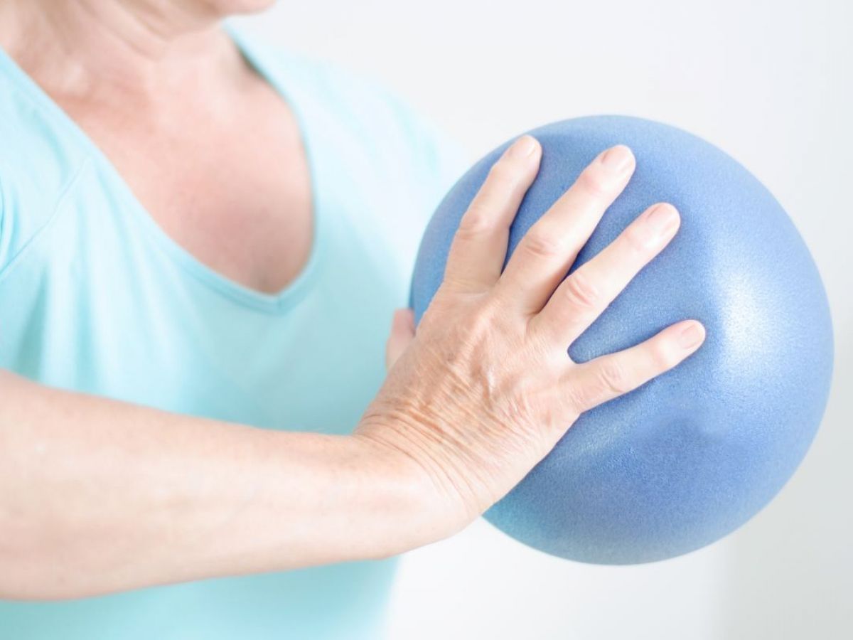 Hand drückt einen blauen Gymnastikball ein, Kräftigungs‑ oder Mobilisationsübung 
