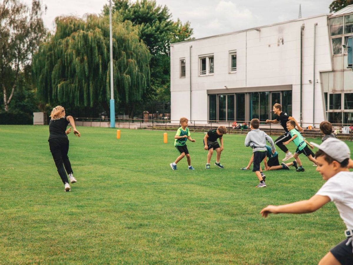 Kinder spielen Mannschaftssport auf dem Rasenplatz.
